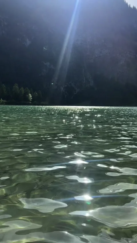 Sunlight sparkling on clear alpine lake water surface Bavaria Stockbeeldmateriaal 341768873