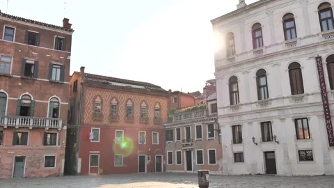 Sunlight spills over a quiet Venetian square lined 스톡 동영상 314667678
