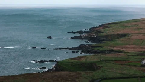 Sunlight spills through clouds as green fields meet the ocean in Dunquin Stock Footage 328471533