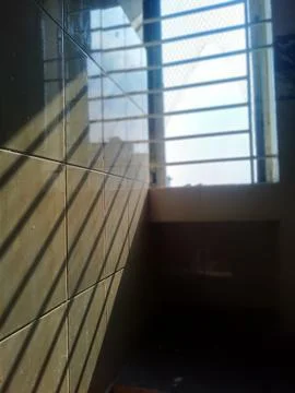 Sunlight streaming through barred window creating dramatic shadows on tiled wall Stock Photos