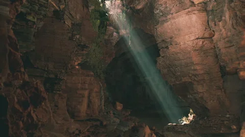 Sunlight streaming through a cave opening in a serene natural landscape Stock Footage 304463161