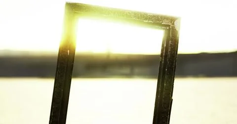 Sunlight streaming through an empty frame in an outdoor setting at sunset 库存插图