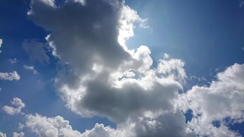 Sunlight streaming through fluffy clouds in blue sky. Stock Photos