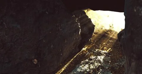 Sunlight streaming through rocky cave entrance during bright midday hours 스톡 일러스트