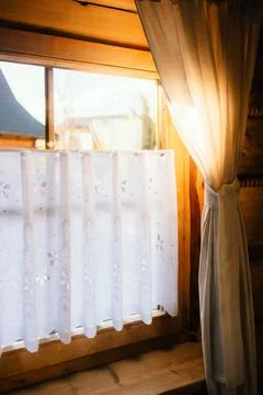 Sunlight streaming through sheer white curtains in cozy wooden cabin creates Foto stock