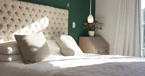 Sunlight streaming through window casting patches across bedspread and pillows Stock Footage 313944425