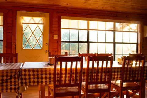 Sunlight streams into a rustic home with a long table ready for a dinner Foto stock