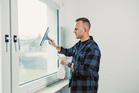 Sunlight streams through clean windows as a diligent worker scrubs away dir.. Stock-Fotos