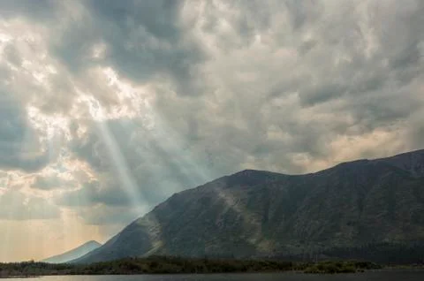 Sunlight streams through the clouds onto the mountains at the south end of Fish Stock Photos
