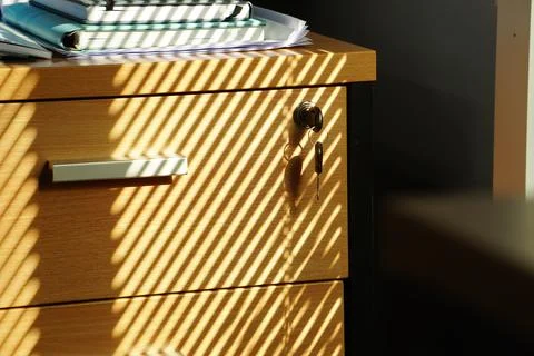 The sunlight streams through the window blinds, casting a striped shadow pattern Stock Photos