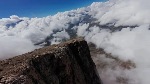 Sunlight striking rugged mountain peak towering above dense cloud layer Stock Footage 304527005