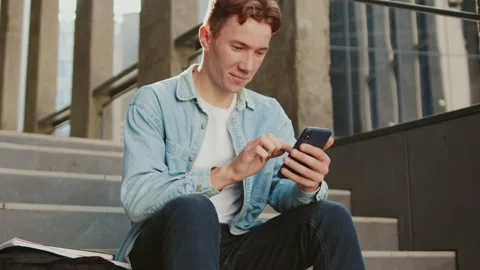 At sunlight student young handsome man with red hair sitting on stairs near Stock Footage 142050232