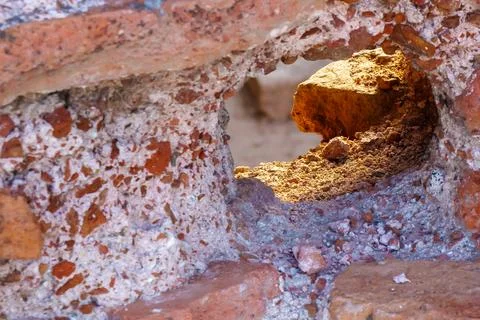 Sunlight through a hole in old brick wall revealing rough stone texture Stock Photos