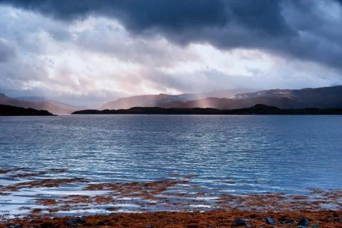 Sunlight through storm clouds over a Scottish Loch Stock Photos