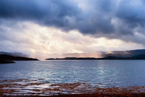 Sunlight through storm clouds over a Scottish Loch Stock Photos