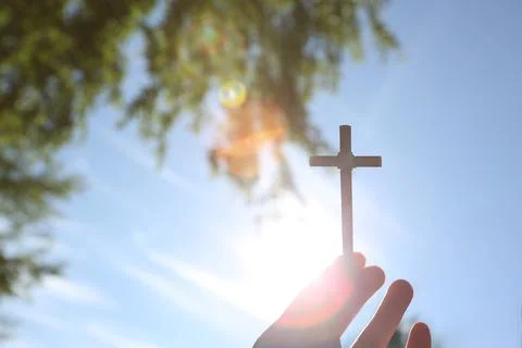Sunlight through the trees illuminates the cross of Jesus Christ Stock Photos