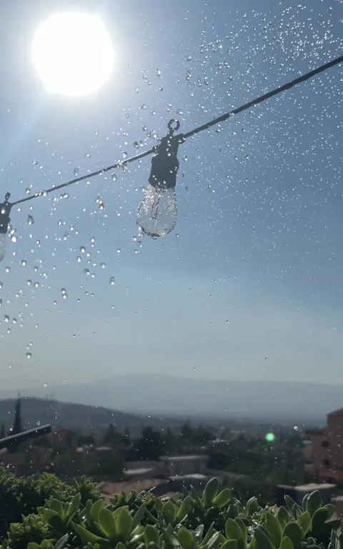 Sunlight Through Water Droplets with Hanging Bulb and City View 4K Stock Footage 345146931