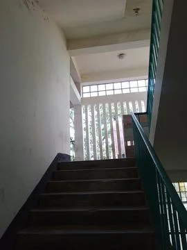 Sunlight through window creating geometric shadow patterns on staircase floor Stock Photos