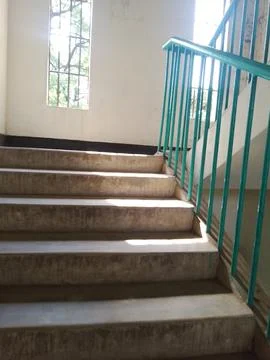 Sunlight through window creating geometric shadow patterns on staircase floor Stock Photos