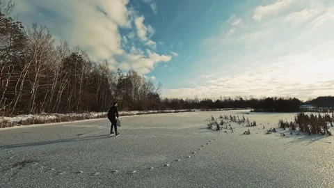 At sunlight top view of business man with bag skates on frozen ice in forest Stock Footage 215053181