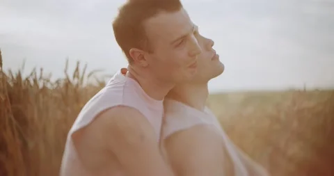 At sunlight two men gay hugging on field at the wheat smiling looking lovely at Stock Footage 200957110