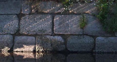 Sunlight from water ripples in river, reflected on old stone wall Video stock 134504924