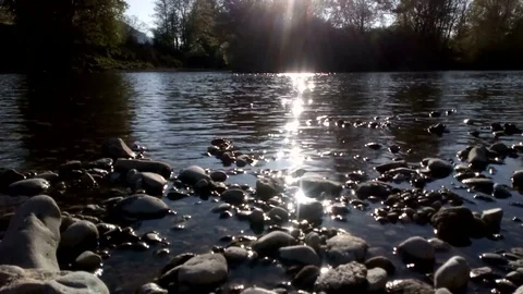 Sunlight on waving river water, flowing over stones bottom. Evening relax view Stock Footage 129673316