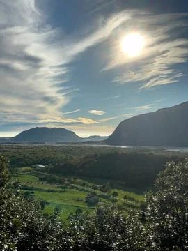Sunlit Alpine Valley with Dramatic Clouds 스톡 사진
