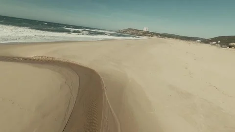 Sunlit beach curves with gentle waves lapping sand Video stock 341822060