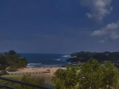 Sunlit beach meets ocean waves with calm blue skies Fotos de archivo