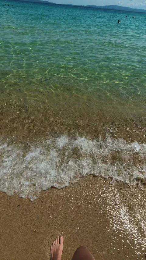 Sunlit beach meets turquoise ocean under clear sky. Trani Ammouda, Vertical Stock Footage 340651997