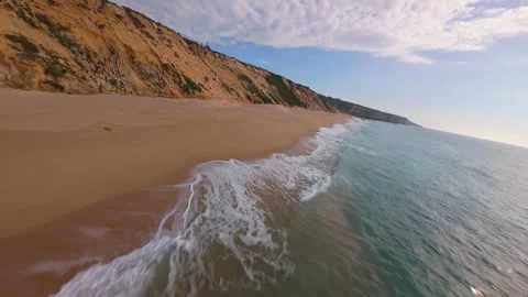 Sunlit beach with rugged cliffs meets turquoise sea Stock Footage 340225424