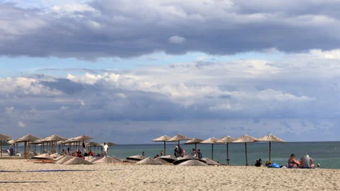 Sunlit beach scene with straw umbrellas and clouds. Stock Footage 287920511