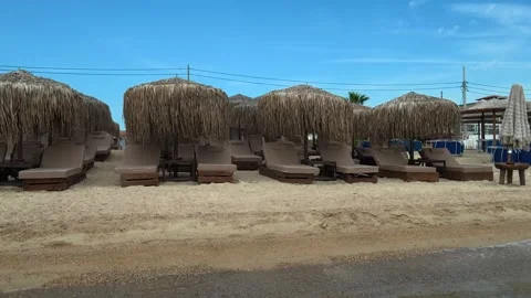Sunlit beach with straw umbrellas and lounge chairs. Trani Ammouda, Greece Stock Footage 339619756