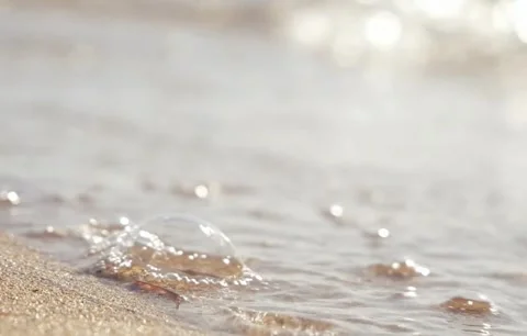 Sunlit Beach Waves with Sparkling Bokeh on Golden Sand Shore Video stock 343320414