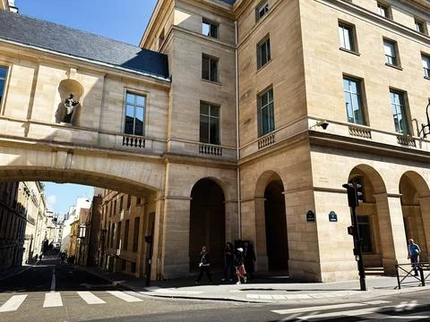 Sunlit classical stone building with archway and statue over a quiet Paris .. Stock Photos