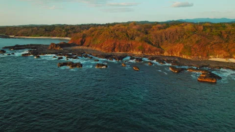 Sunlit cliffs with scattered rocks along tropical Costa Rica pacific coastline Stock Footage 341298419