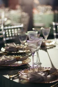 Sunlit close-up of luxury table setting with glowing crystal glasses Stock Photos