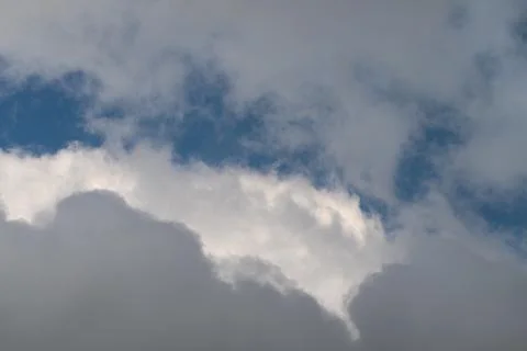 Sunlit cloud edges glow against sky, luminous rims and soft highlights create Stock Photos