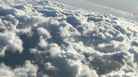 Sunlit clouds drift by in flowing streaks as the aircraft cuts through the sky Stock Footage 323202522