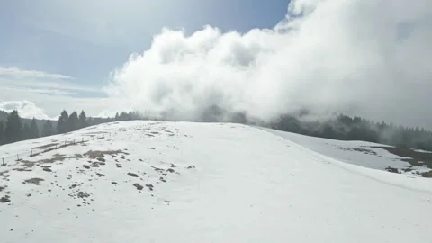 Sunlit clouds drift over snowy hilltop on Cansiglio plateau Stock Footage 318609650