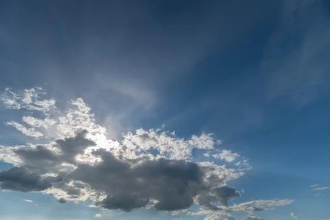 Sunlit cloudscape with rays breaking through blue sky Stockfoto's