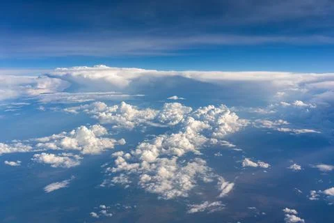 Sunlit cloudscape spreading below airplane at cruising altitude Stock Photos