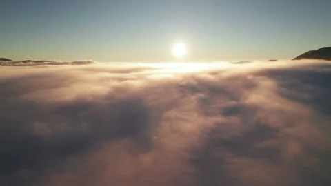 Sunlit cloudscape stretches across mountain valley from aerial perspective Stock Footage 346726238