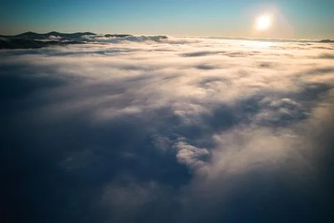 Sunlit cloudscape stretching across mountain valleys in early morning light Stock-Fotos