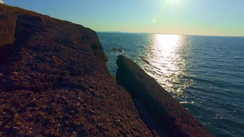 Sunlit coastal cliffs and calm blue ocean water, natural landscape scenery Stock Footage 340450170