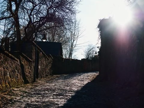 Sunlit Cobblestone Path with Stone Walls Stock-Fotos