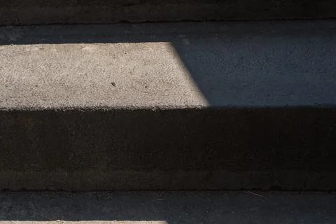 Sunlit concrete steps with strong diagonal shadow and textured surfaces in Stock Photos