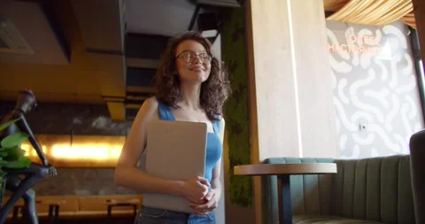 Sunlit Connections: The Tech-Savvy Charm of a Young Woman in a Blue Top with a Stock Footage 242899489