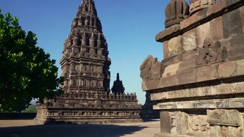 Sunlit courtyard view reveals a towering Prambanan shrine beyond ancient st.. Stock Footage 341545209